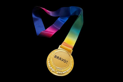 Gold medal with 'BRAVO!' text and a rainbow ribbon on a dark background